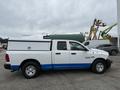 A 2016 RAM 1500 pickup truck with a white exterior and blue accents featuring a truck bed cover and a crew cab design