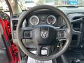 Steering wheel of a 2013 RAM 2500 with controls and a central logo along with instrument gauges visible in the background