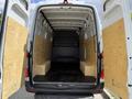 Interior of a 2022 Mercedes-Benz Sprinter van with open rear doors showing a spacious empty cargo area with wooden panels on the sides and benches along the walls