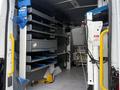 A 2023 Ford Transit van interior equipped with shelving and storage units designed for tools and equipment organization