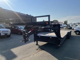 A black 2020 Load Trail 28 Foot Gooseneck trailer with a wooden deck and a gooseneck hitch is parked in an outdoor lot