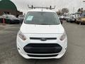 A white 2017 Ford Transit Connect with a black front grille and roof rack positioned in the foreground