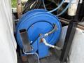 A blue hose reel mounted on a metal framework with visible hoses and fittings attached to it