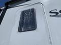 A white travel trailer with the name "Solitude" displayed prominently and a window covered in plastic wrap, secured with tape