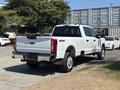 A 2023 Ford F-350 Super Duty truck with a white exterior and chrome accents parked with the tailgate visible