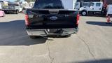 A black 2016 Ford F-150 truck with a distinctive rear design featuring a chrome bumper and Ford logo on the tailgate