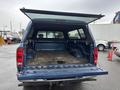 The image shows the open bed of a blue 2006 Dodge Ram 2500 pickup truck with a cap on the back and a clean lined interior
