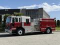 A red and white 1994 Volvo FE 42 fire truck with chrome details and emergency lights on top parked on a surface road