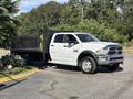 A 2014 RAM 5500 flatbed truck with a white exterior parked at an angle with a wooden flatbed attached to its rear