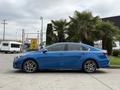 A blue 2021 Kia Forte is parked, showcasing its sleek design and alloy wheels with a streamlined profile
