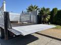 A 2019 Ford F-550 truck with a flatbed and a folded-down ramp at the back ready for loading cargo