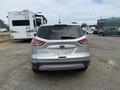 A 2014 Ford Escape in silver color parked with its rear facing the viewer showing the tail lights and back bumper