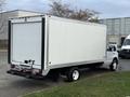 A 2022 Ford E-450 box truck in white with a flatbed rear and dual rear wheels parked at an angle with a plain exterior and no visible markings
