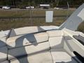 A 2013 Larson 238 boat with white and gray upholstery featuring cushioned seating in a sunlit area