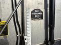 A metal salt discharge gate with a measuring scale attached to a 2013 Freightliner 114SD truck