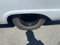 A close-up of a 1962 Ford 2WHDR wheel with a flat tire and a shadow cast on the pavement