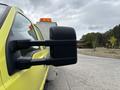 A 2010 Ford F-550 Super Duty with a prominent side mirror and bright yellow exterior