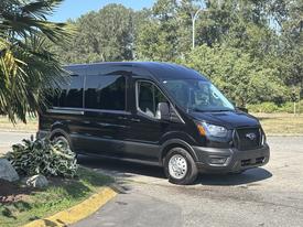 A black 2025 Ford Transit 350 van parked with its front slightly turned to the left showcasing the vehicle's modern design and large windshield