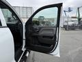 A white 2016 GMC Sierra 1500 with the driver's side door open showcasing a black interior and control panel visible inside