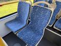 Interior view of two empty bus seats with blue fabric featuring a geometric pattern on a public transit bus