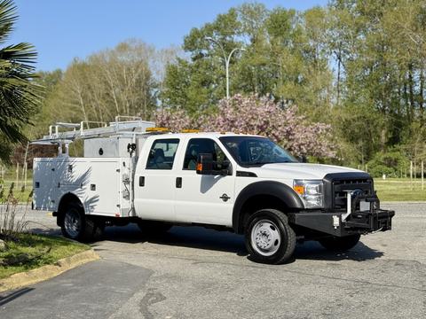 2015 Ford F-550 service truck with a utility box and ladder rack in a white finish parked on a driveway