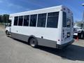 2020 Chevrolet Express bus with large windows and a white exterior parked at an angle with a gray lower body