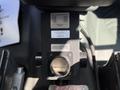 A black control unit is positioned in the center console of a 2018 Ford Transit with various labels and warning notices attached to its surface