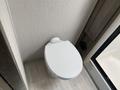 A white toilet with a rounded seat positioned against a textured wall inside a recreational vehicle