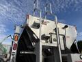 A 2013 Freightliner 114SD truck with a silver spreader attachment and metal ladder on the rear side