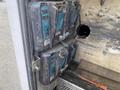A 2015 Ford F-550 with a large storage compartment displaying stacked Makita battery chargers and batteries secured with a strap