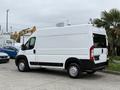 A white 2020 RAM Promaster van with a high roof and rear windows parked at an industrial location