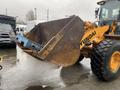A 2016 Hyundai HL940 front-end loader with a large metal bucket is positioned in the foreground, showcasing its yellow and black design with heavy-duty tires