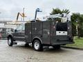 A 2006 Ford F-450 SD utility truck with a black service body and a mounted crane on the back