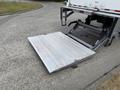 A silver hydraulic lift gate is lowered at the back of a 2022 International MV607 truck with a flat surface for loading and unloading cargo