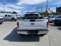 A rear view of a 2015 Ford F-150 with a silver color and a black bed liner visible on the truck bed