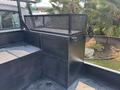 A metal mesh and black steel storage compartment mounted in the bed of a 2006 Sterling Acterra truck