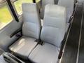 Two gray passenger seats with a ribbed design and seatbelts in a school bus interior
