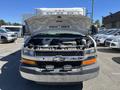 A 2013 Chevrolet Express with its hood raised revealing the engine compartment and components inside