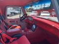 Interior of a 1962 Ford 2WHDR featuring red upholstery a steering wheel and dashboard with gauges and a touchscreen device