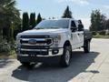 A white 2020 Ford F-350 Super Duty pickup truck with a black bed and chrome accents parked on a driveway
