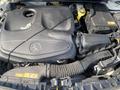 A 2014 Mercedes-Benz CLA-Class engine with a large black cover displaying the Mercedes-Benz logo and various components including hoses and a yellow cap