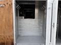 A metal interior of a freight truck with empty walls and hooks mounted on one side