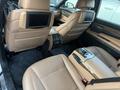 Interior view of a 2011 BMW 7-Series showing tan leather seats with rear entertainment screens and a center console with controls