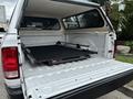 A 2013 RAM 1500 with an open tailgate showing a black bed cover and a storage system in the truck bed