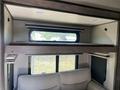 Interior view of a 2021 Grand Design Recreational ST3478MBS showing a sleeping loft with a cushioned surface above a seating area