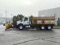 A 2016 International 7400 truck with a yellow plow and salt spreader attached on the back