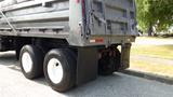 A 2003 International 5600i truck with a grey dump bed and dual rear wheels equipped with mud flaps and visible tail lights