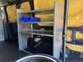 A 2016 Ford Transit 150 with a metal shelving unit containing blue storage bins inside the cargo area