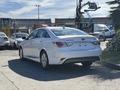 A 2015 Hyundai Sonata parked with its rear facing the viewer showcasing a sleek white exterior and distinctive tail lights