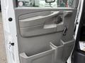 A gray interior door panel of a 2008 Chevrolet Express with a handle a control knob and storage compartments